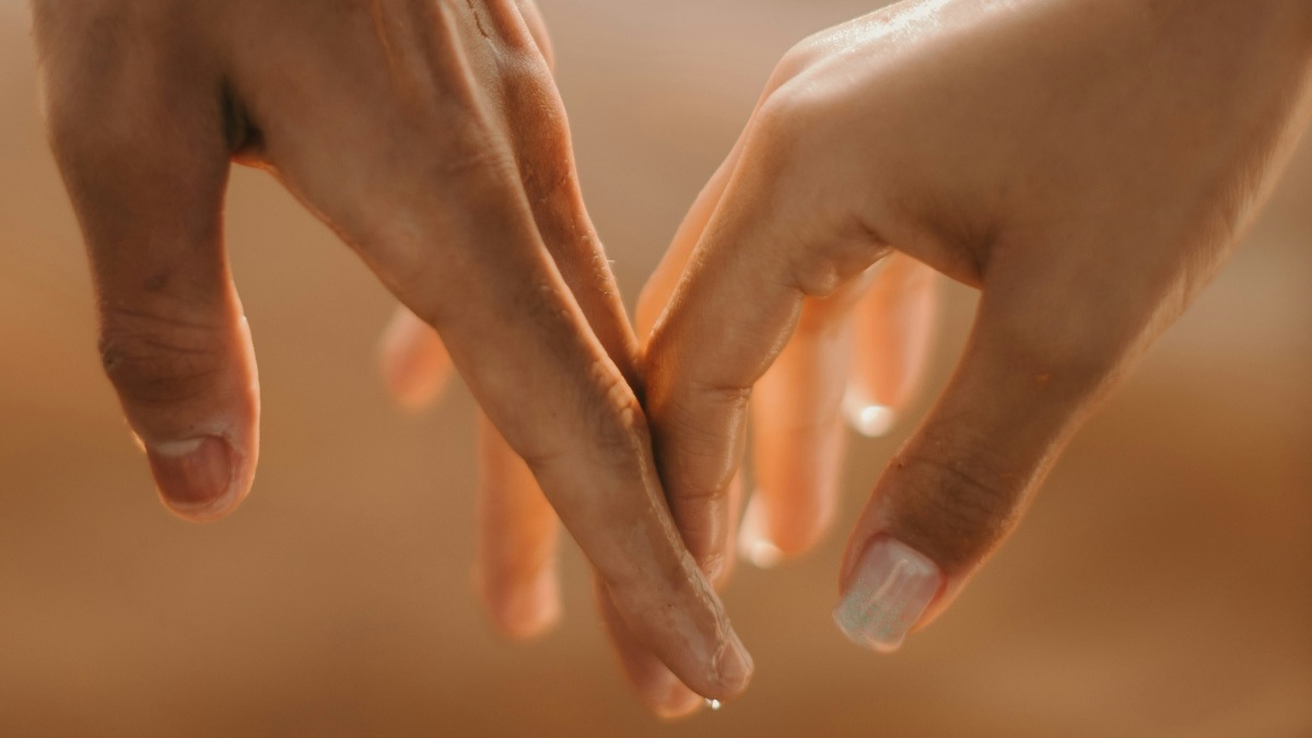 
a balanced couple holding hands over a body of water
