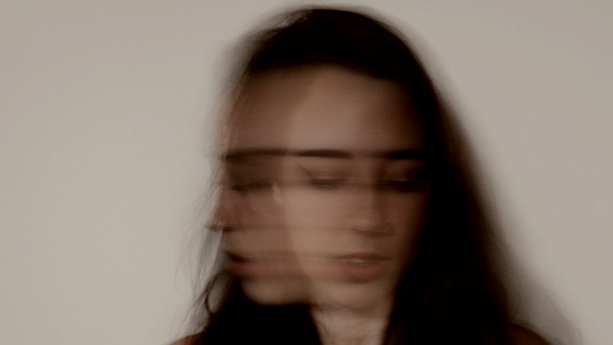 
a blurry photo of a woman against a white wall by Christopher Ott
