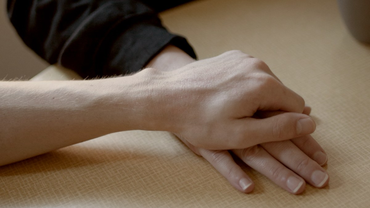 
a close up of a couples hands on a table near a coffee cup by Gabriel Ponton
