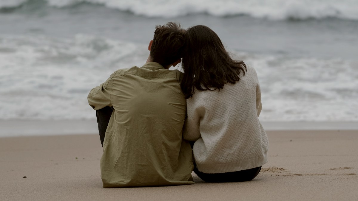 
a-couple-of-people-sitting-on-top-of-a-sandy-beach
