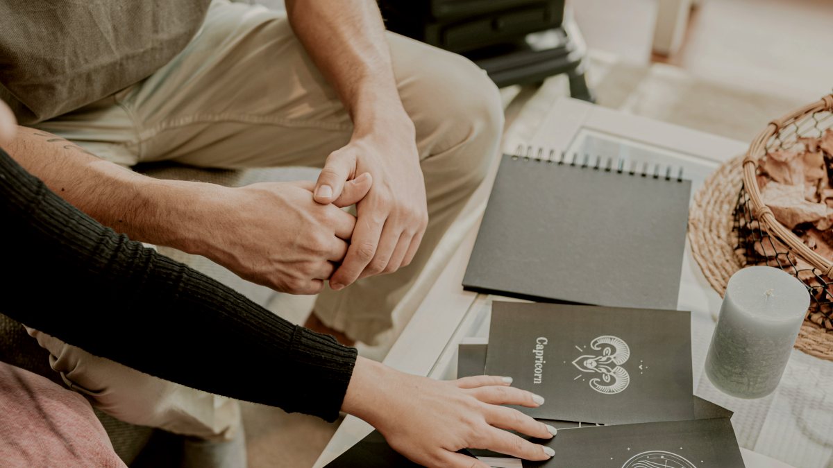
a couple of people that are sitting at a table looking at zodiacs by AC
