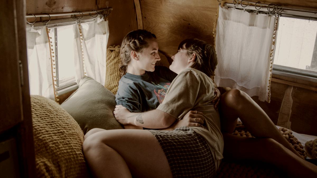 
a couple of women sitting on top of a bed in a cabin by tabitha turner
