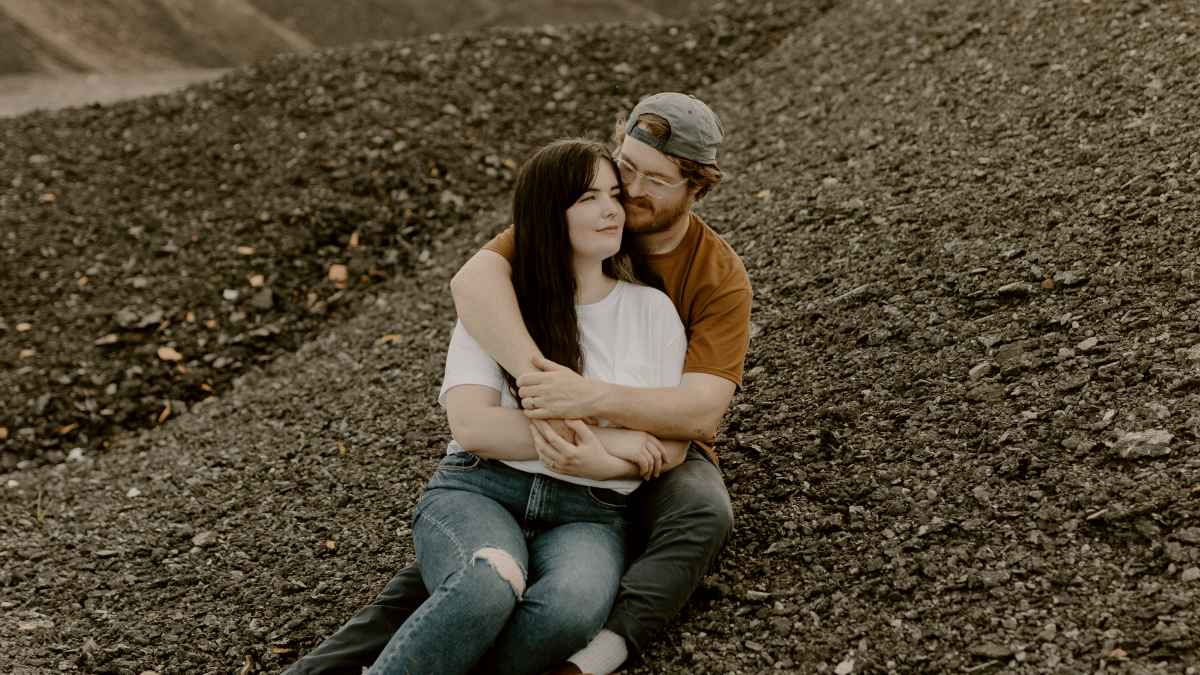 
a-couple-snuggling-on-a-rocky-beach
