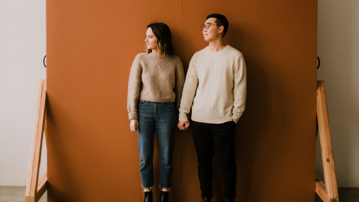 
a-couple-standing-in-front-of-a-backdrop
