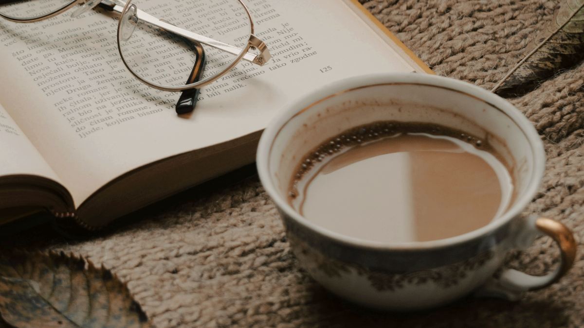 
a cup of coffee next to an open book
