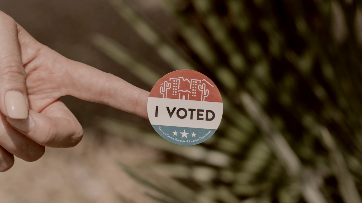 
a-finger-holding-an-i-voted-sticker
