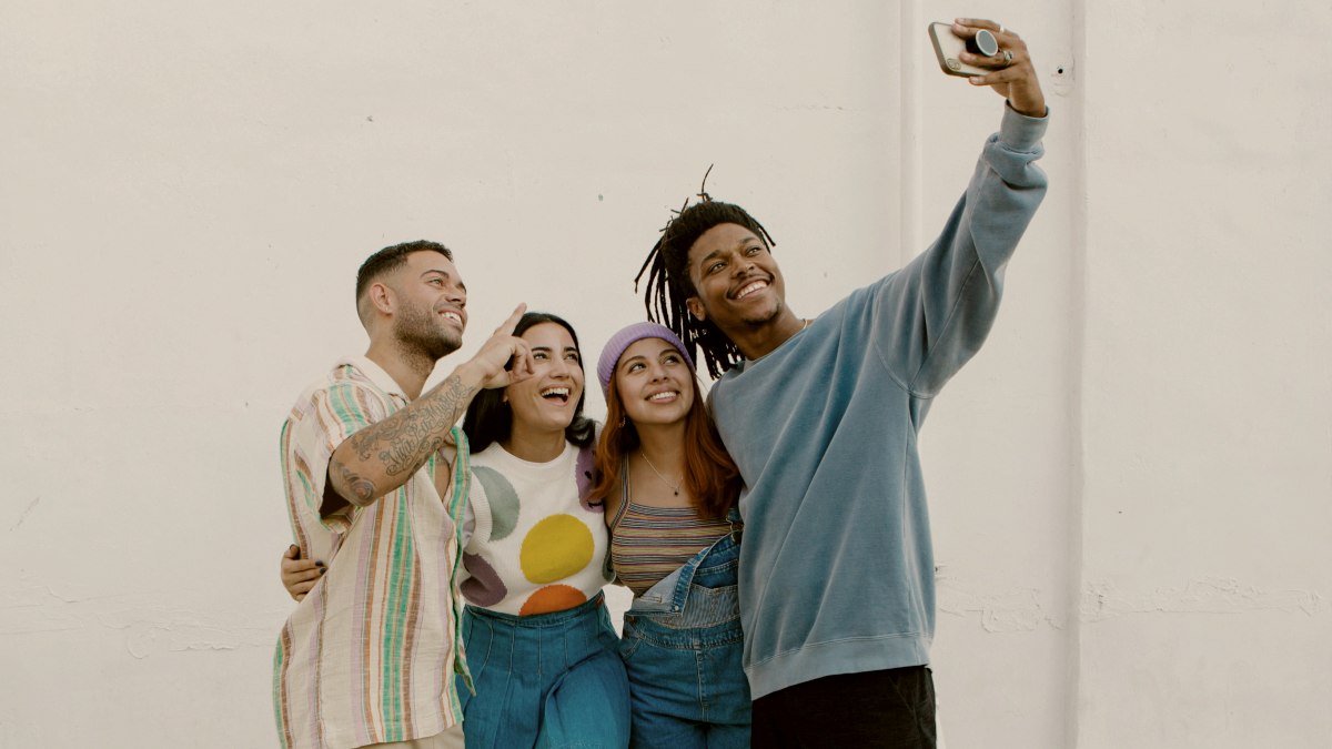 
a group of friends taking a selfie together in front of a white wall by Lia Bekyan
