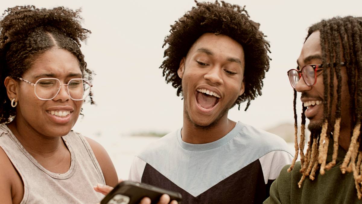 
a group of people standing next to each other laughing with phone in hand by Nappy
