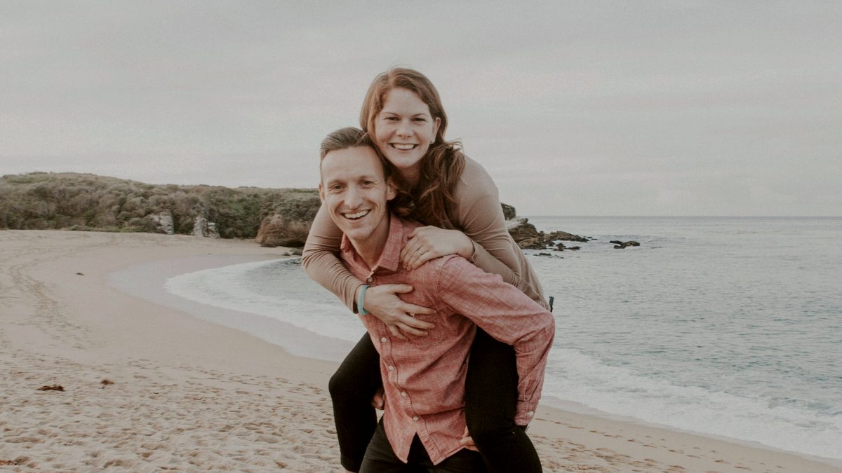 
a-happy-couple-piggy-backing-on-the-beach
