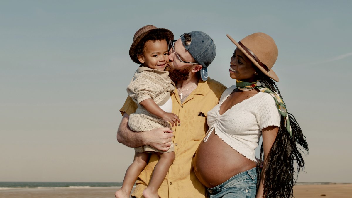 
A happy family of three poses on a sunny beach by Toa Heftiba
