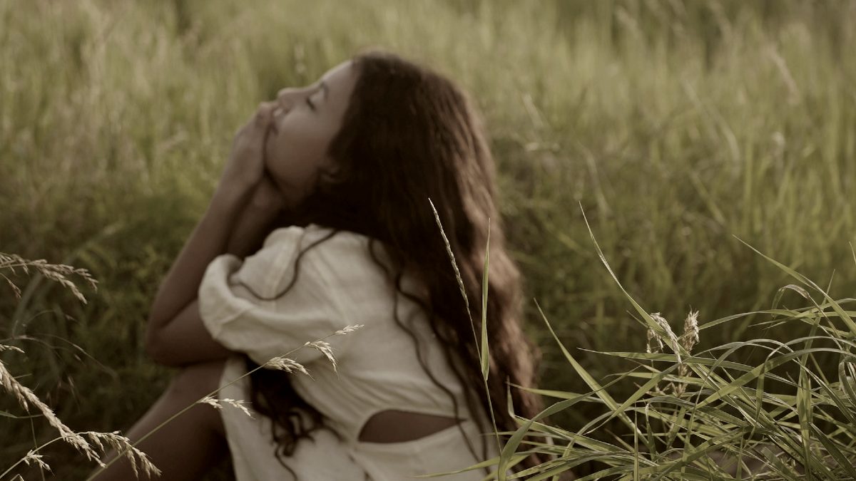 
a-little-girl-sitting-in-a-field-of-tall-grass
