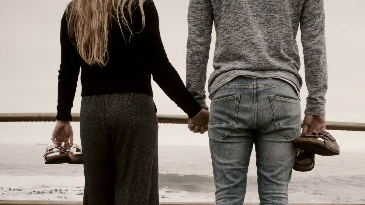 
a-loveless-couple-holding-hands-on-a-rainy-beach
