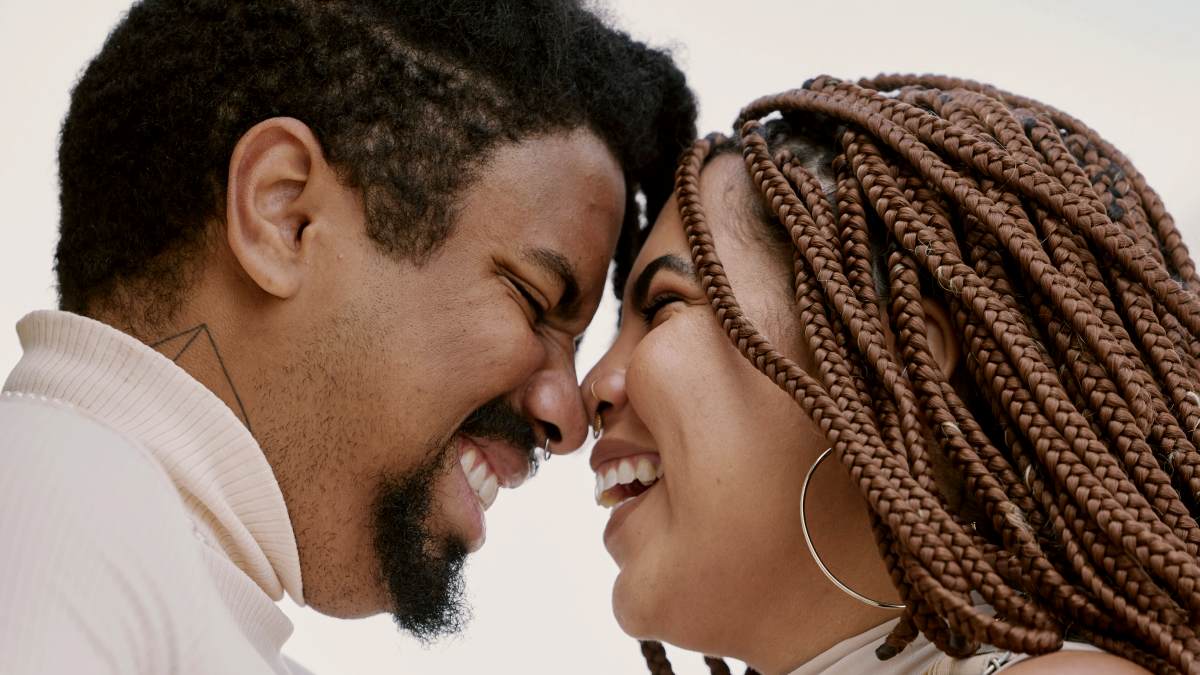 
a man and a woman are smiling together with their noses touching
