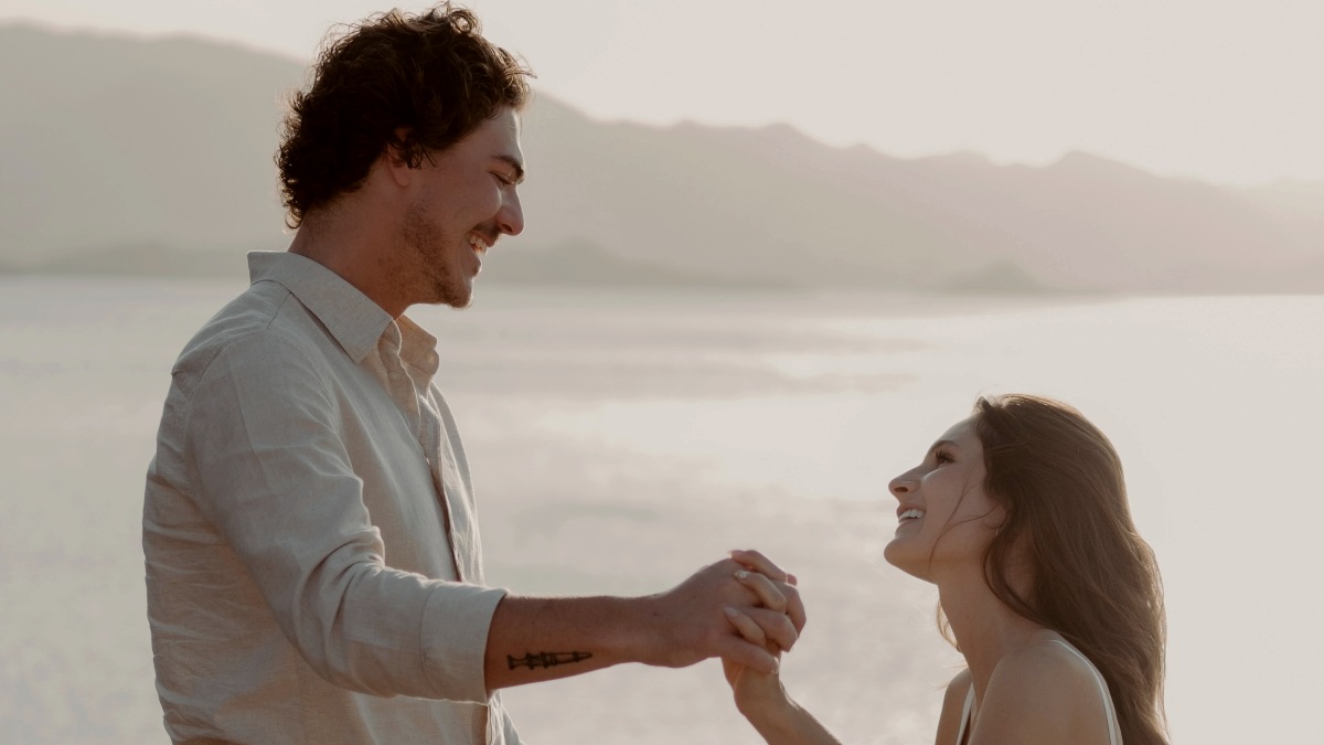 
a man and a woman gazing into each others eyes as they hold hands near the water
