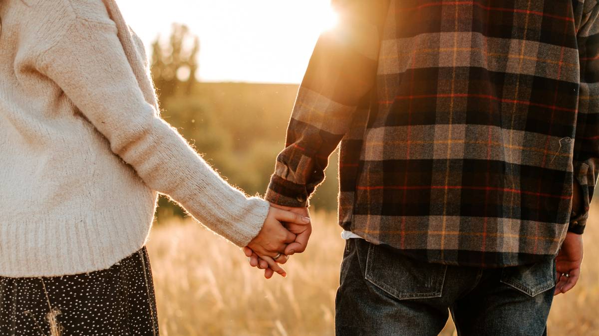 
a man and a woman holding hands in a field by Kateryna Hliznitsova

