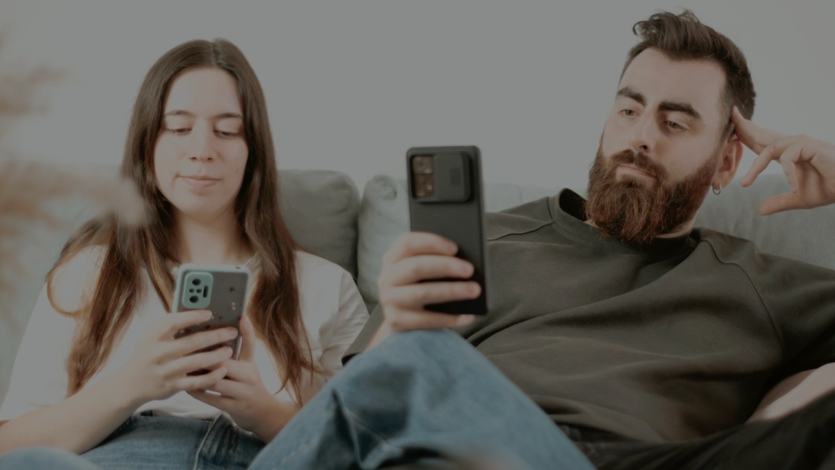 
a man and a woman sitting on a couch looking at their phones by A. C.
