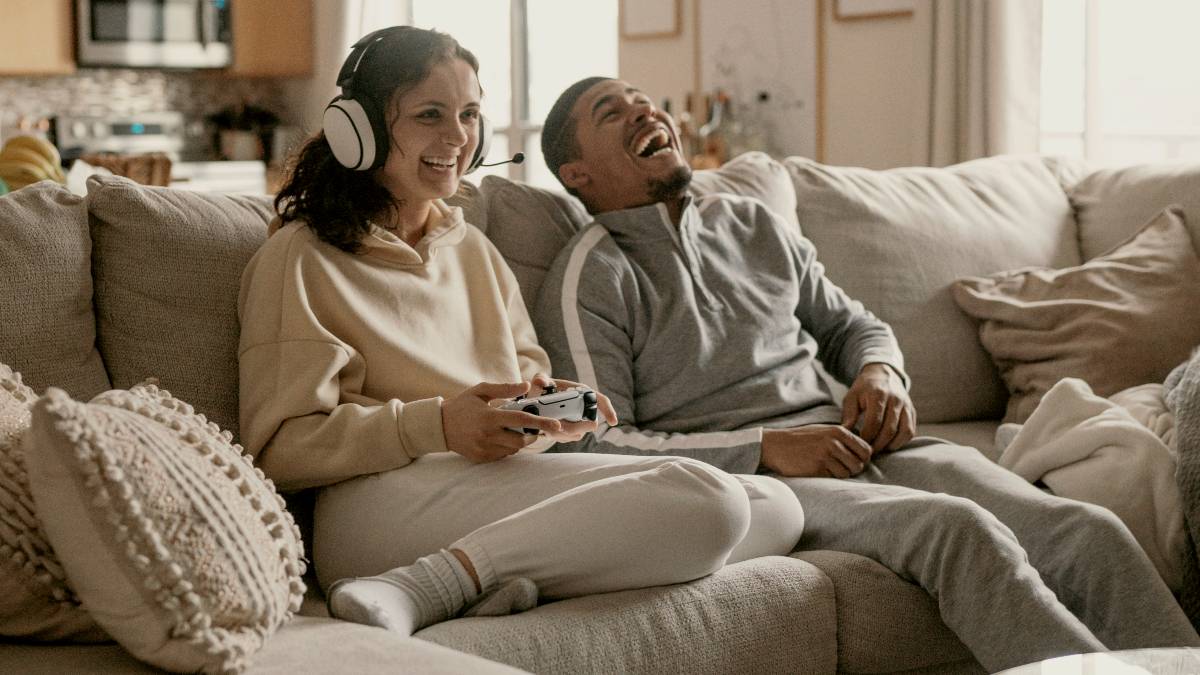 
a man and a woman sitting on a couch playing on a ps5
