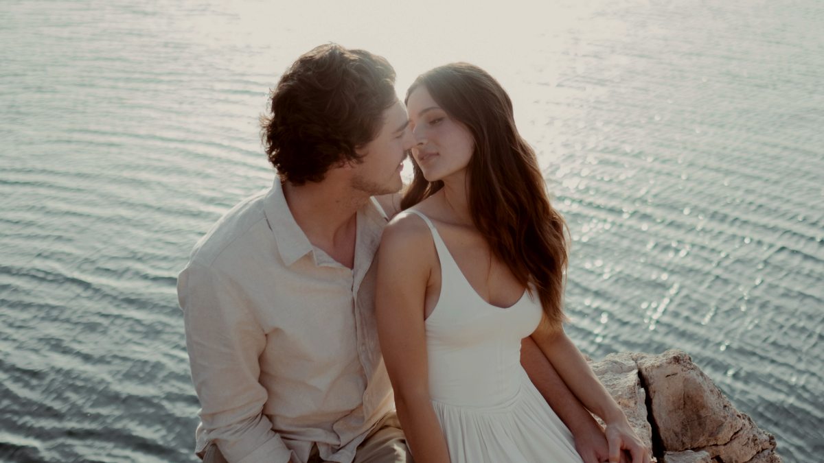 
a-man-and-a-woman-sitting-on-a-rock-by-the-water
