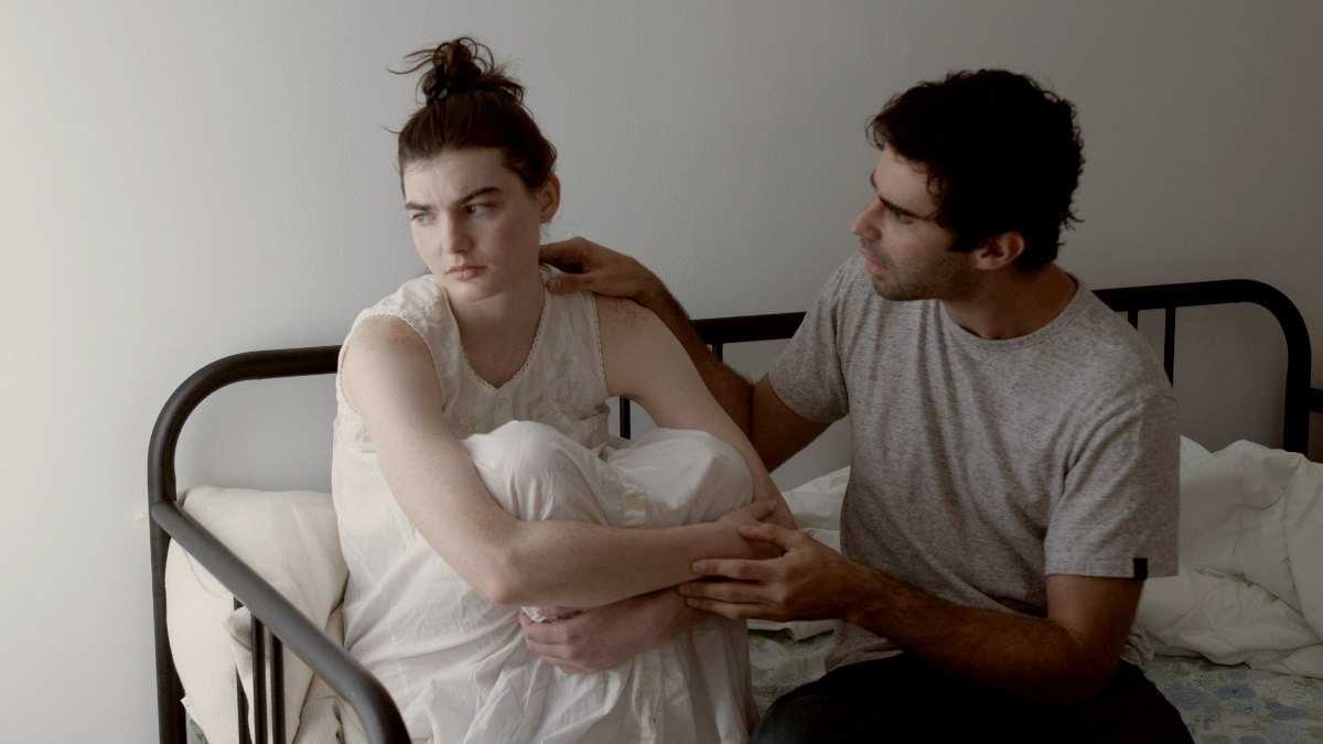 
a man apologizing to a woman sitting next to him on a bed by Gabriel Ponton
