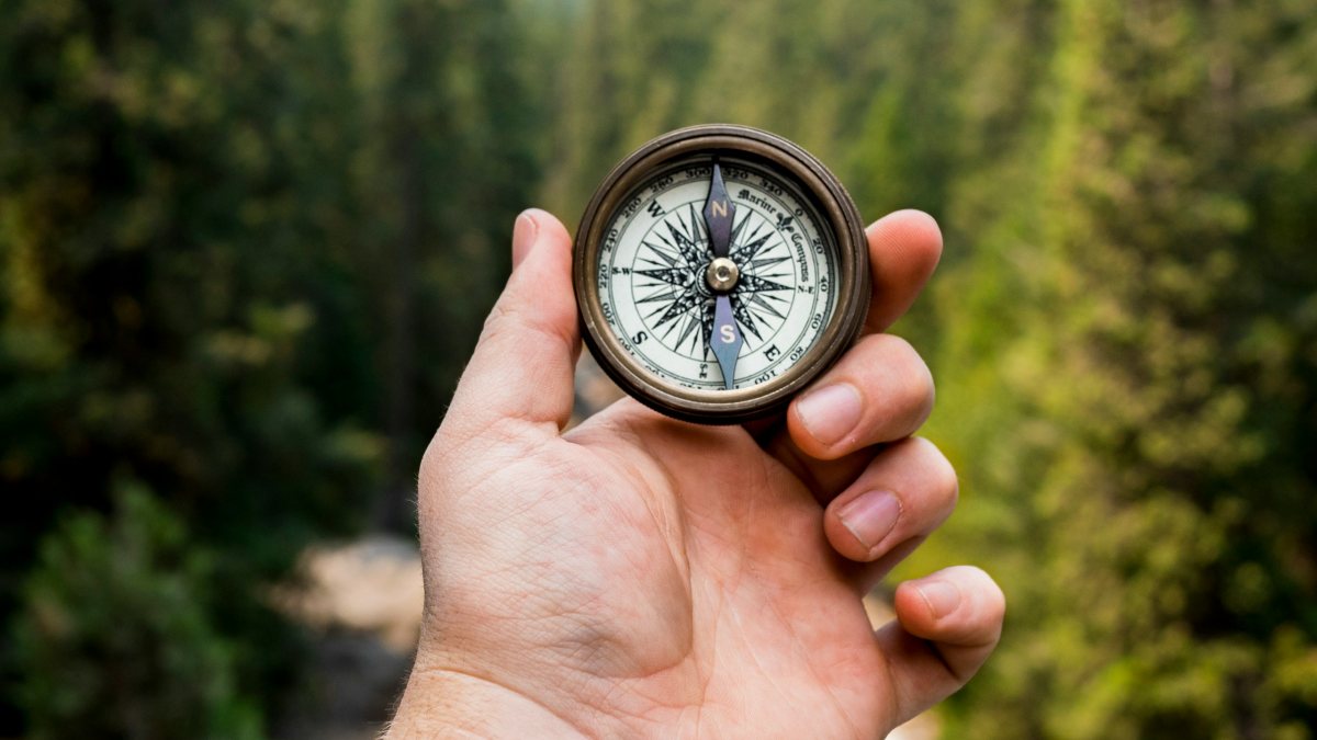 
a man holding a compass in a serene setting on the search for purpose in life 
