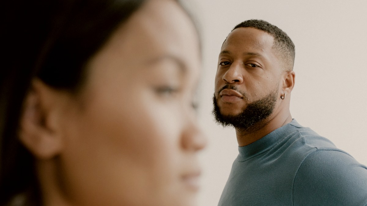 
a man in a blue shirt looking at a woman out of focus by lia bekyan
