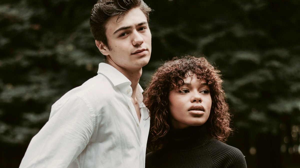 
a man in white and woman in black standing together in a field
