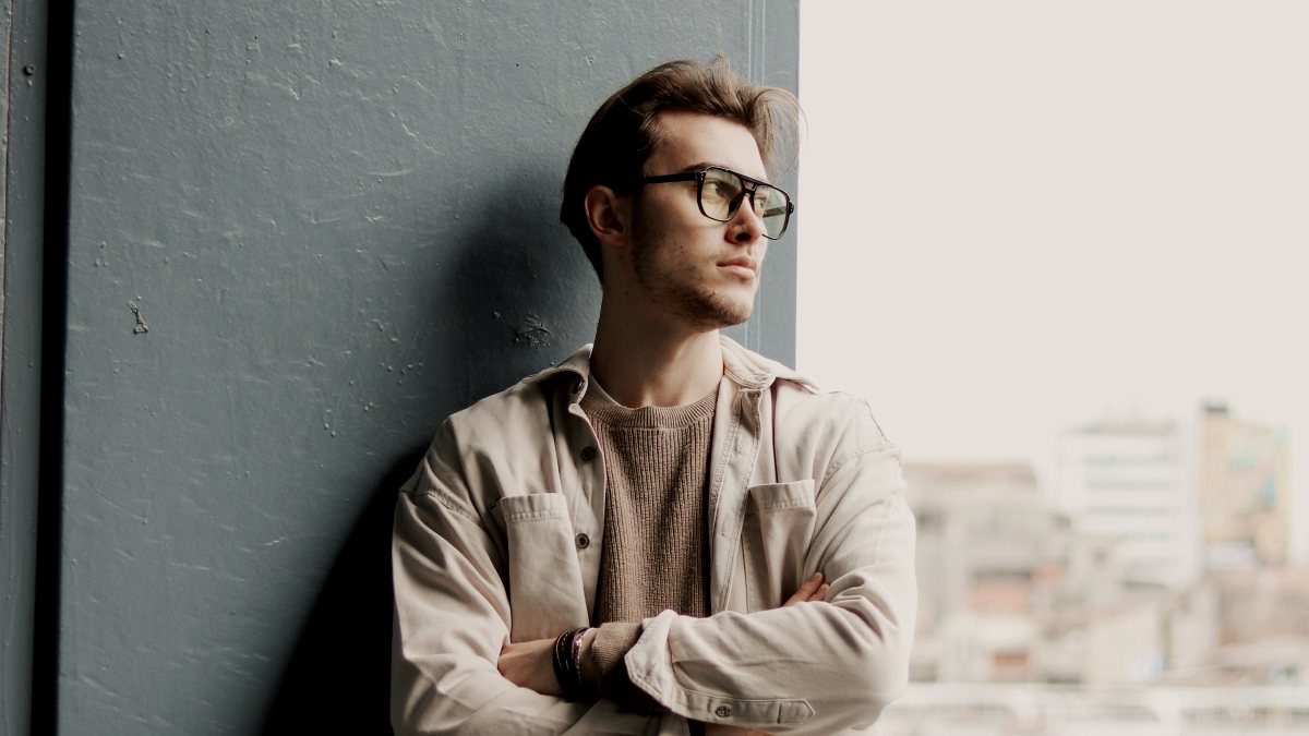 
a man leaning against a wall with his arms crossed
