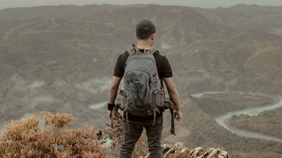 
a man standing on top of a mountain with a backpack
