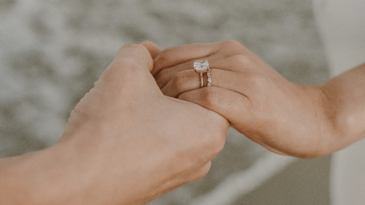 
a pair of hands holding a wedding ring
