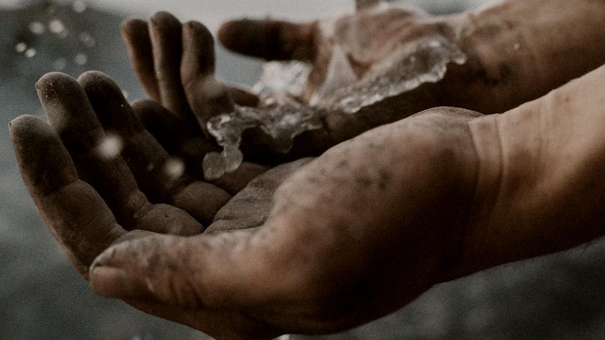 
a person holding out their dirty hands with water pouring onto them by Elisabeth Jurenka
