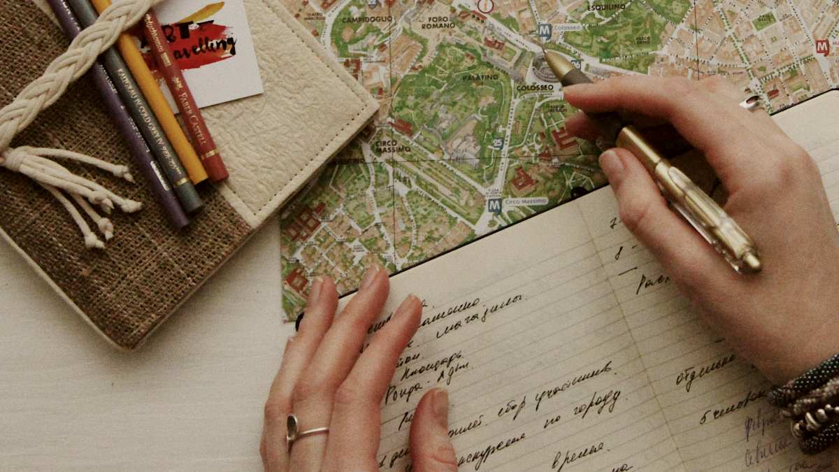 
a person journaling next to a pair of eyeglasses on map
