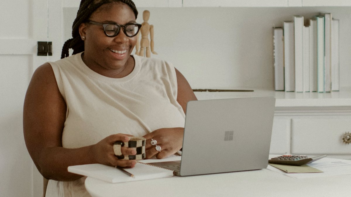 
a person sitting in a room with a coffee in front of their laptop
