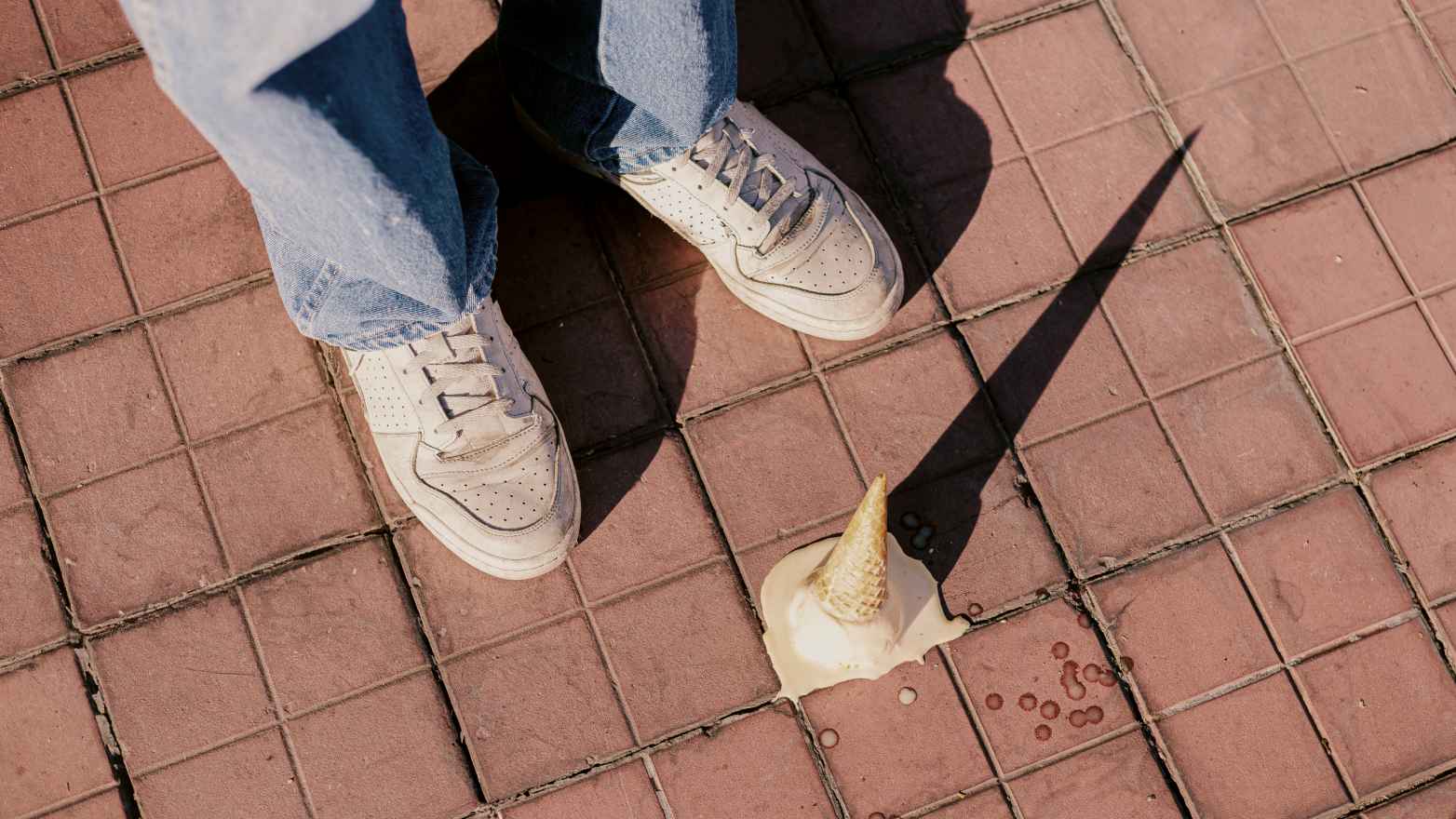 
A person standing on a sidewalk with a dropped ice cream cone by Josué Sánchez
