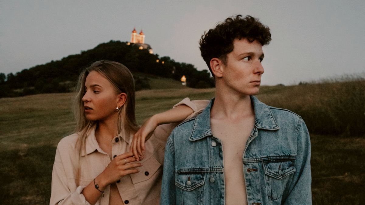 
A portrait of young couple standing in nature in countryside looking away from each other
