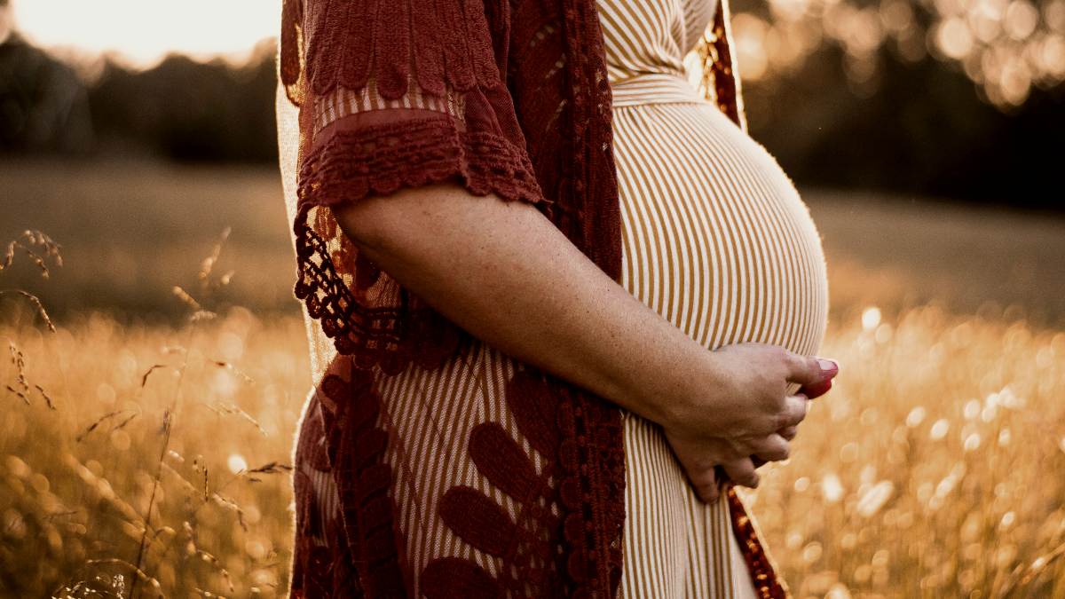 
a-pregnant-woman-standing-in-a-field
