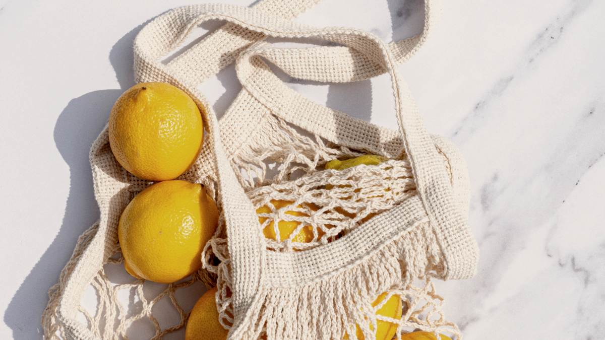 
a reusable fruit bag filled with lemons sitting on top of a white counter
