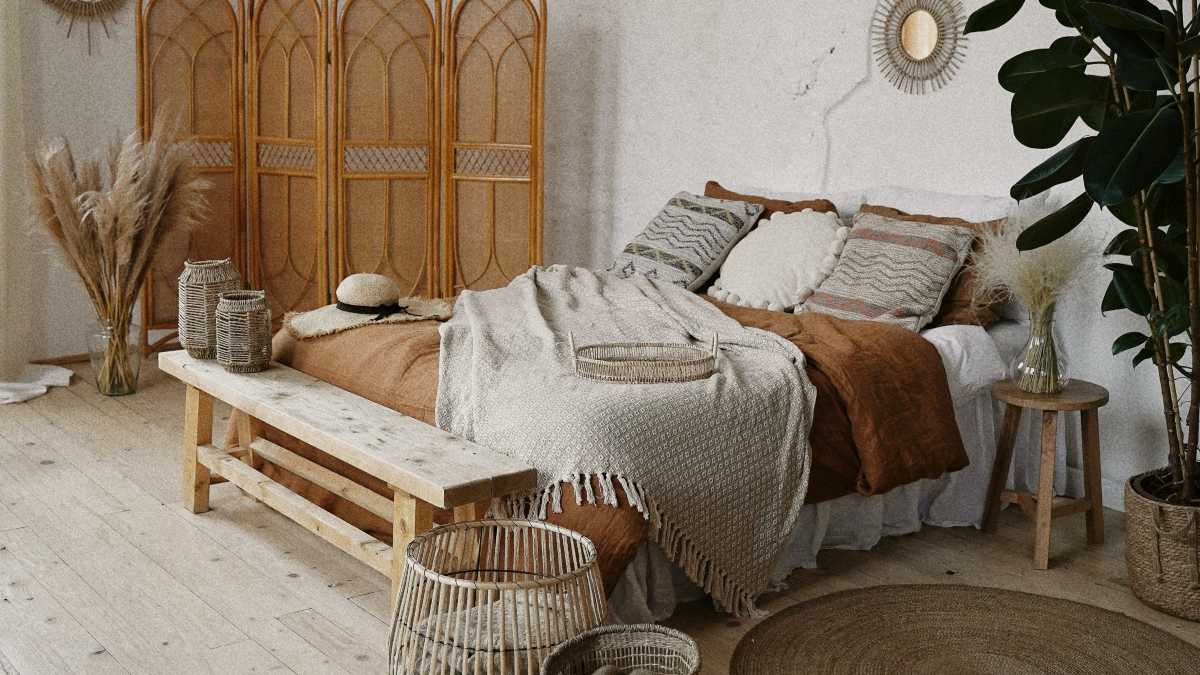 
a rustic styled bedroom with a bed, divider, plants, and a neutral brown color scheme
