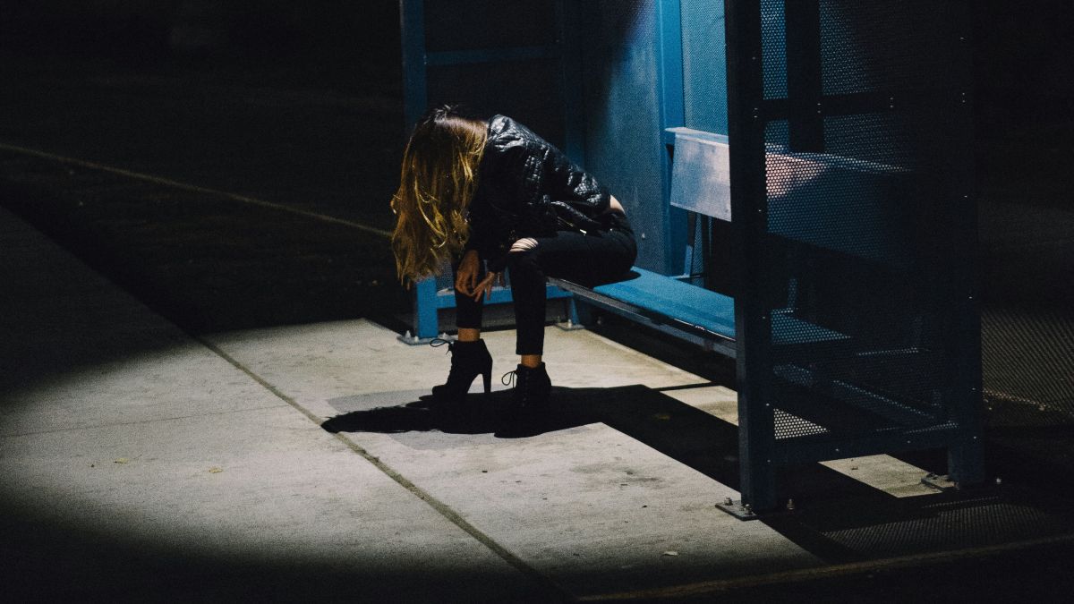 
a sad woman at a bus stop after experiencing a painful rejection
