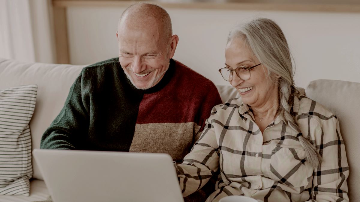 
A senior couple sitting on a sofa and looking at a laptop screen by Getty Images
