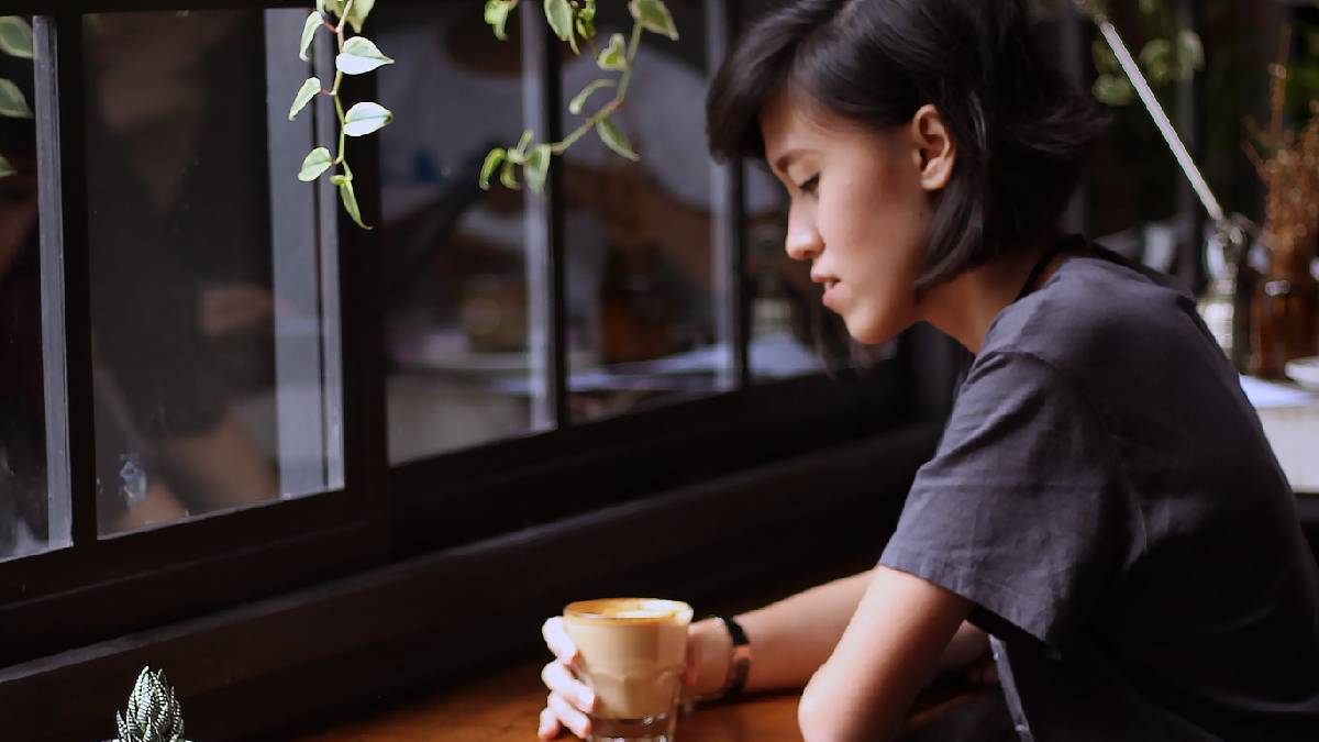 
A woman drinking coffee by herself because she enjoys being alone, single, and not tied down in a relationship
