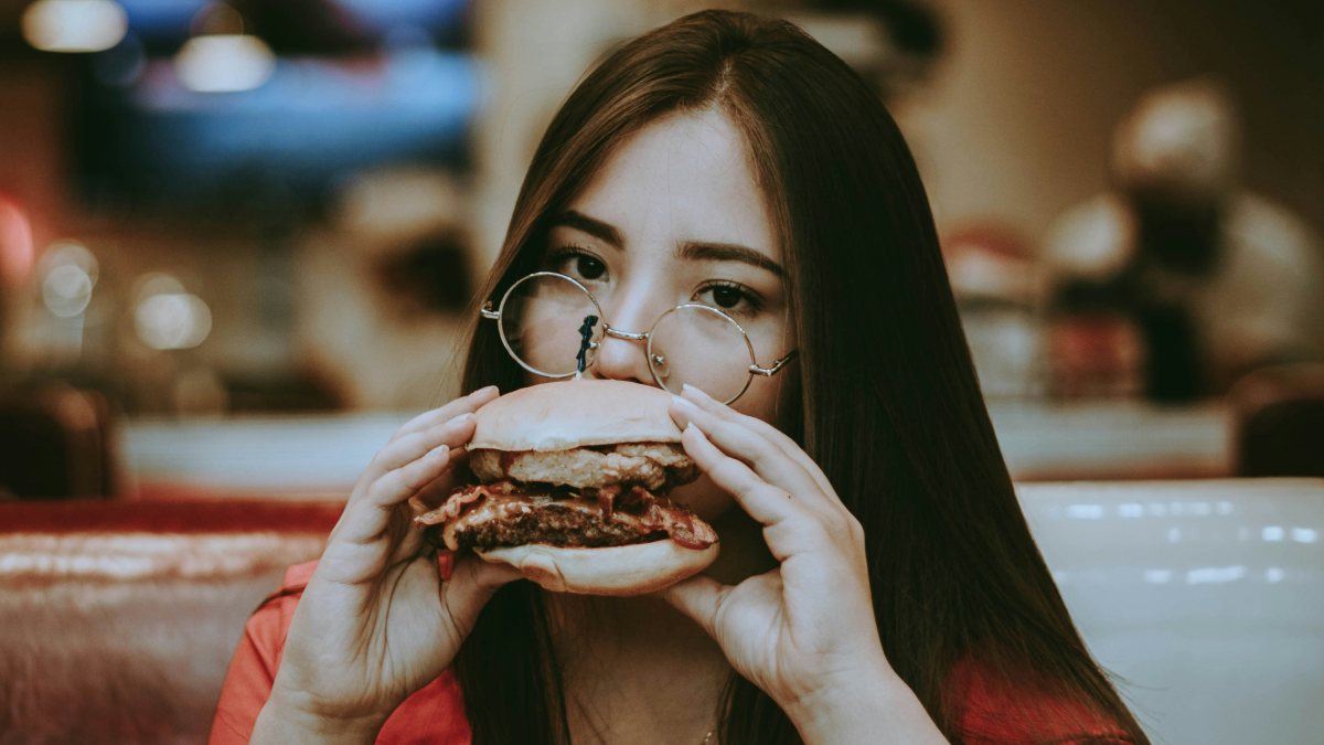
a-woman-eating-a-burger
