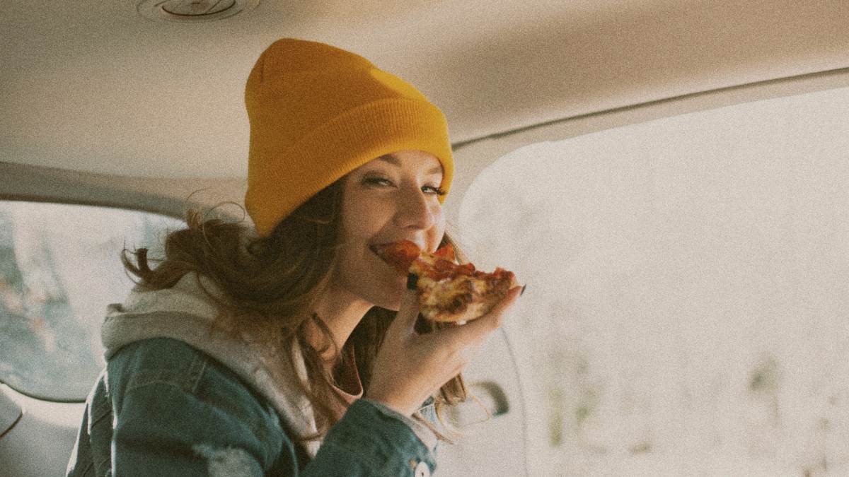 
a-woman-eating-a-pizza-in-a-car
