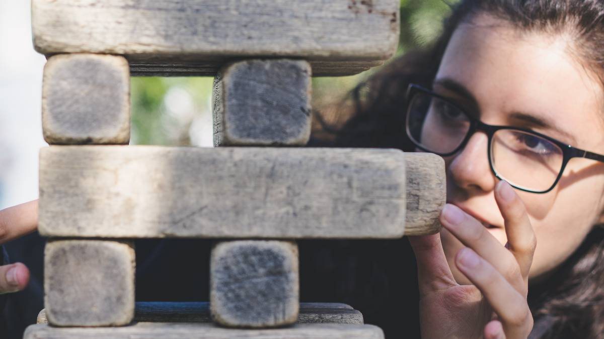 
a woman focusing really hard while playing a game of life size jenga
