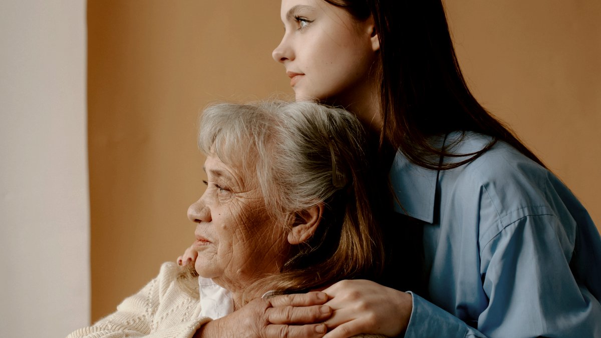 
a woman hugging a woman who is sitting on a chair
