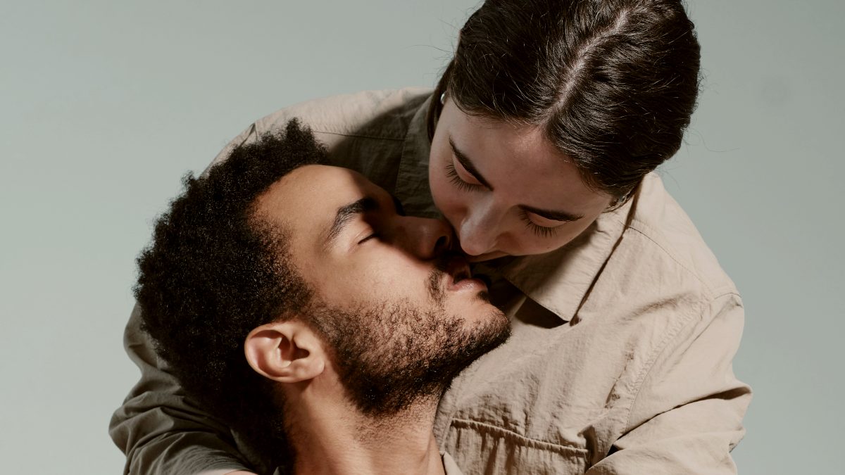 
a woman hugging her partner from behind and kissing him
