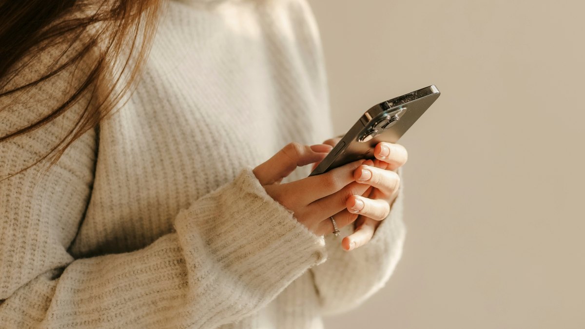 
a woman in a fleece sweater looking at her phone by Natali Hordiiuk
