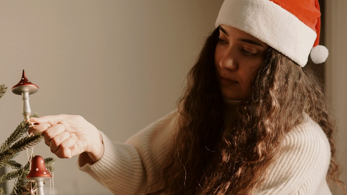 
A woman in a santa hat decorating a christmas tree
