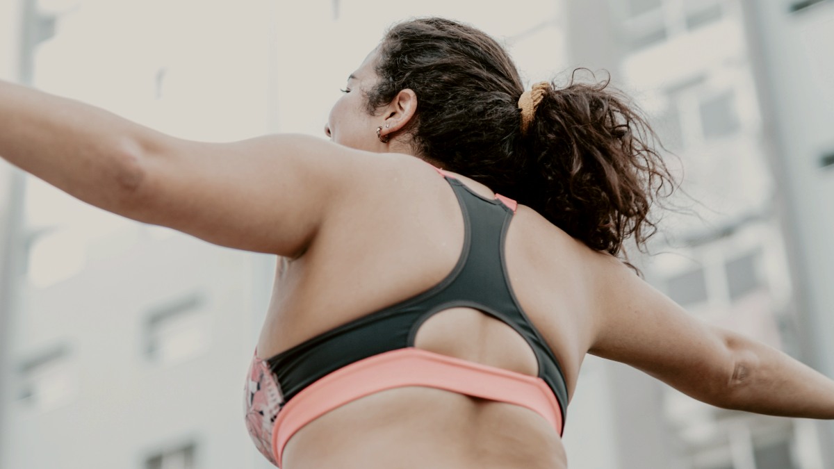 
a woman in a sports bra top and black shorts pictured from behind by AC

