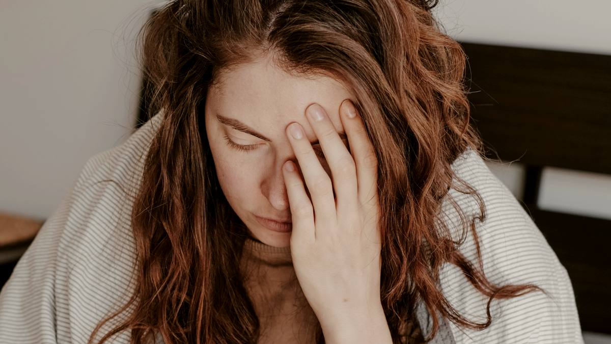 
a-woman-in-bed-covering-her-face-with-her-hands
