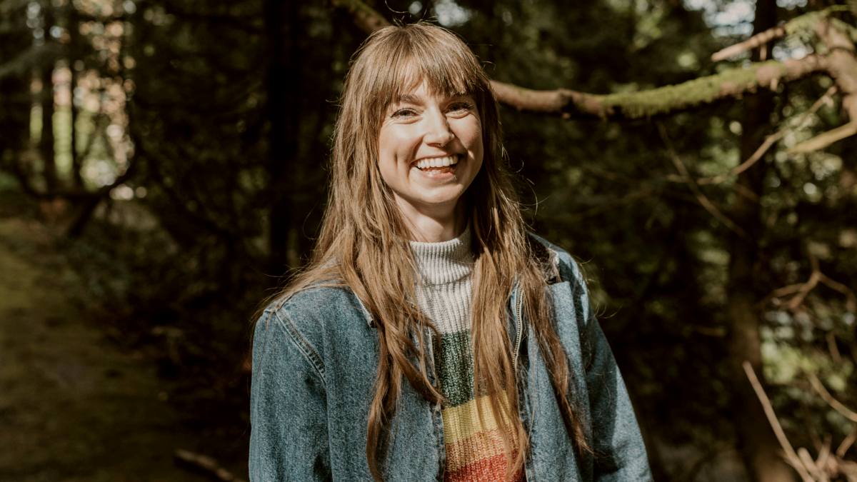 
a woman in denim jacket standing in front of some trees smiling at the camera by Sandra Seitamaa
